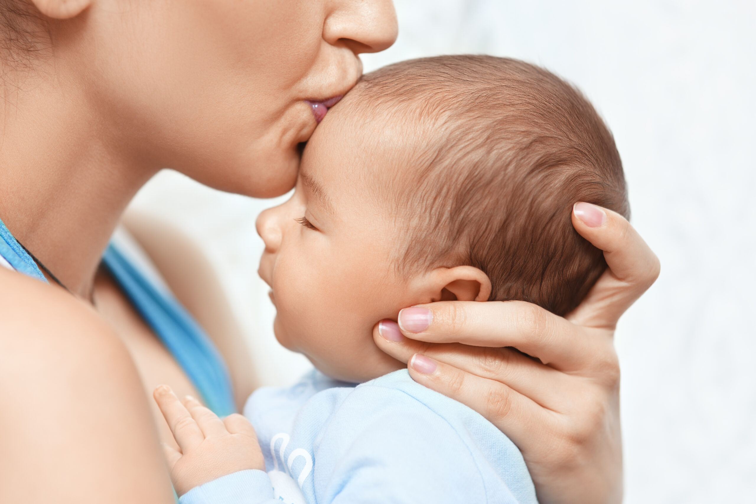 mother holding and kissing newborn baby